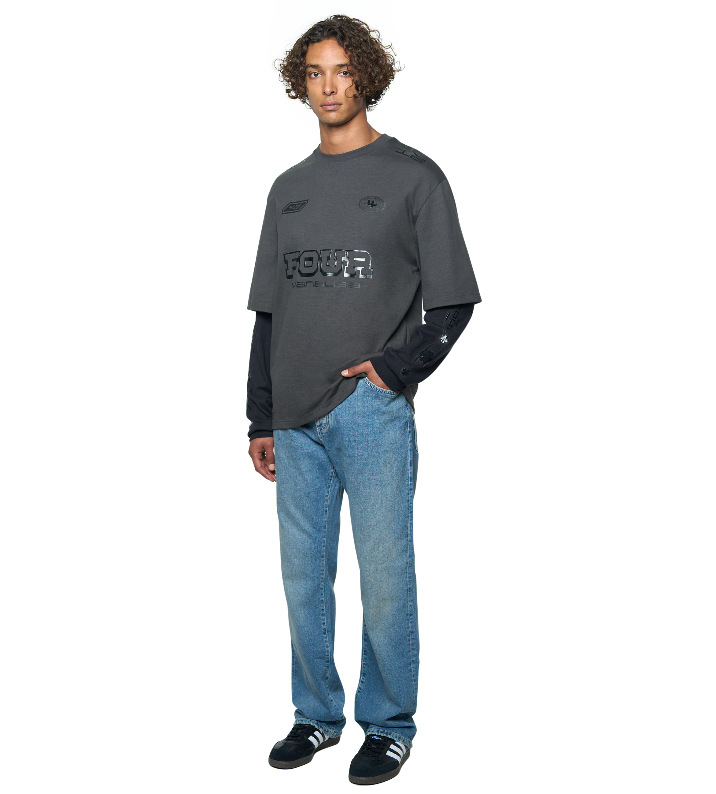 Man wearing a dark gray oversized t-shirt with a logo and blue jeans on a white background